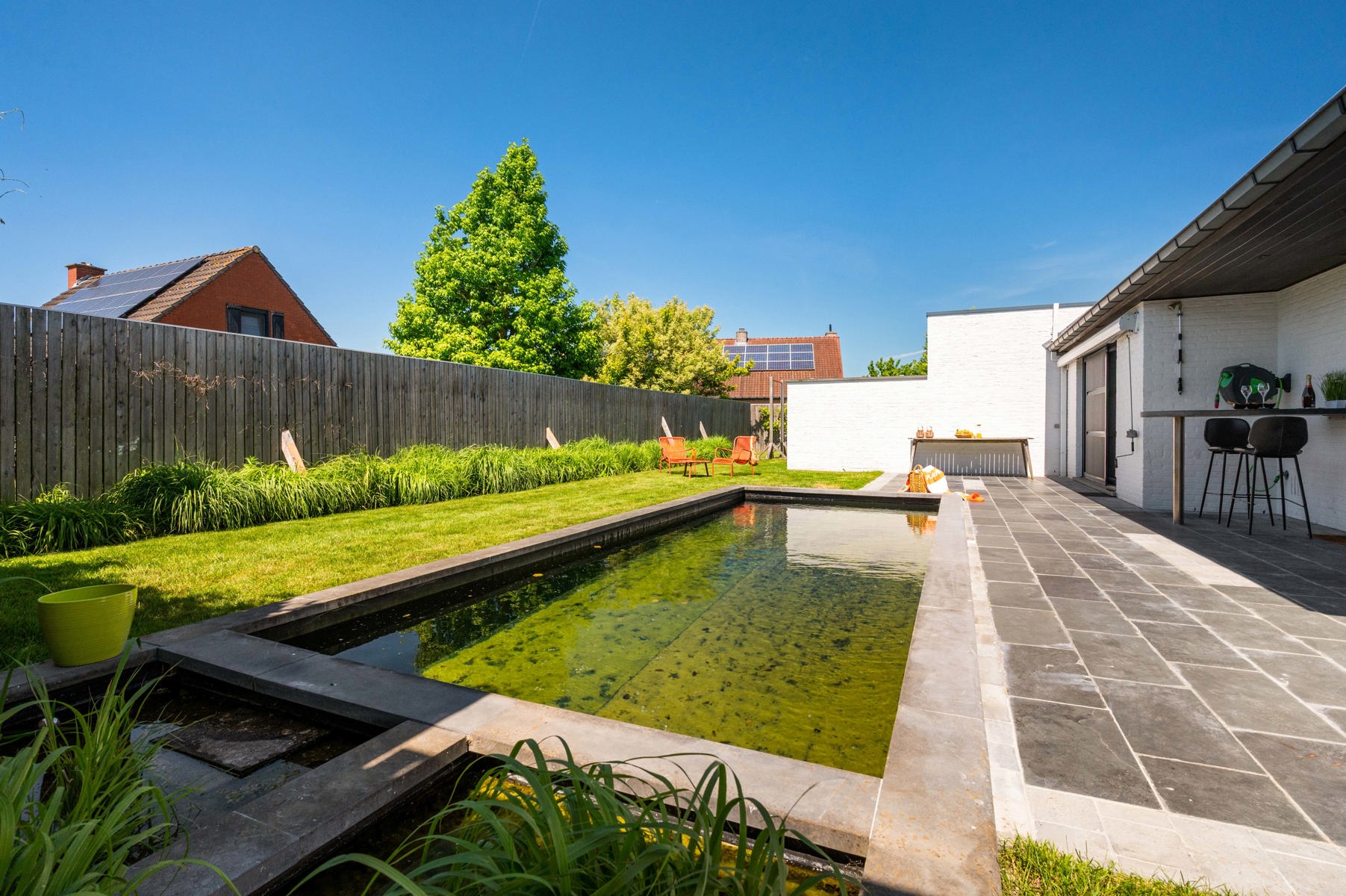 Knappe eigentijdse villa met zwemvijver én praktijkruimte waar wonen en werken perfect gecombineerd kan worden dankzij de extra praktijkruimte !Bezoekmoment : vrijdag 19 en zaterdag 20 juni mits afspraak ! De woning biedt lichtrijke leefruimtes met zicht op de zonnige tuin en het zwembad (8 x 3 m, diepte 1,40 m). Leefkeuken met kwalitatieve inbouwtoestellen, waaronder een steamer. Vier volwaardige slaapkamers en een comfortabele badkamer met zowel ligbad als douche.Praktijkruimte is volledig ingericht met een eigen keuken en badkamer, waardoor tal van mogelijkheden ontstaan voor vrije beroepen, kangoeroewonen of een zelfstandige activiteit.Comfort is hier overal aanwezig dankzij centrale verwarming op aardgas, airconditioning in de volledige woning en praktijkruimte én een gezellige speksteenkachel die zorgt voor extra sfeer en aangename warmte. Ontspannen kan bovendien in de eigen sauna. Afgewerkt met massief parket in praktijk en slaapkamers, screens aan alle slaapkamerramen en praktijk, zonneluifel aan keuken, regenput van 15.000 L, elec conform en klaar voor laadpaal, volledig afgesloten tuin, dubbele garage met sectionale poort.Een ruim tuinhuis en een uitzonderlijk grote oprit met plaats voor maar liefst 10 wagens met brede zijpoort naast de woning.Een unieke eigendom waar ruimte, comfort, privacy en multifunctionaliteit hand in hand gaan!Instelprijs : 695.000 euro Bel of mail voor je afspraak : 056/520.780info@immoyes.bewww.immoyes.be – foto 1